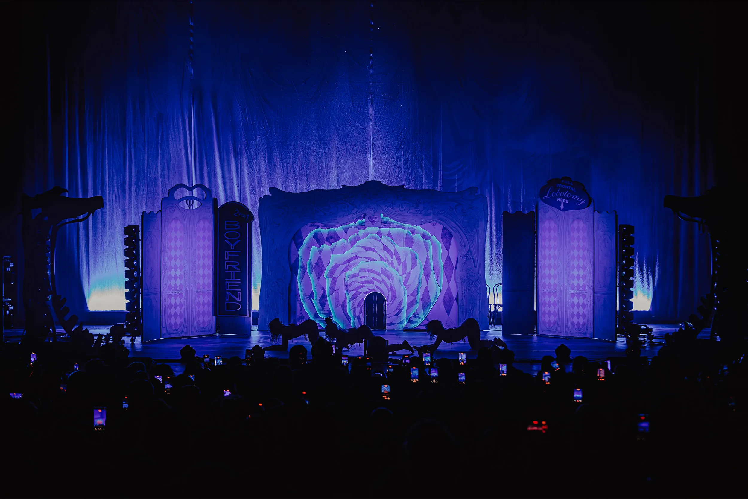 The whole set washed in deep blue and violet, dancers crawling low across the stage in front of the rose