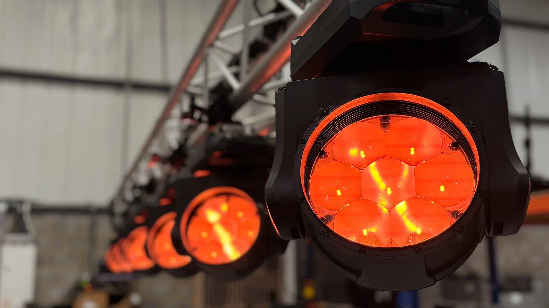 Aura XIP fixtures rigged on truss, lit red.