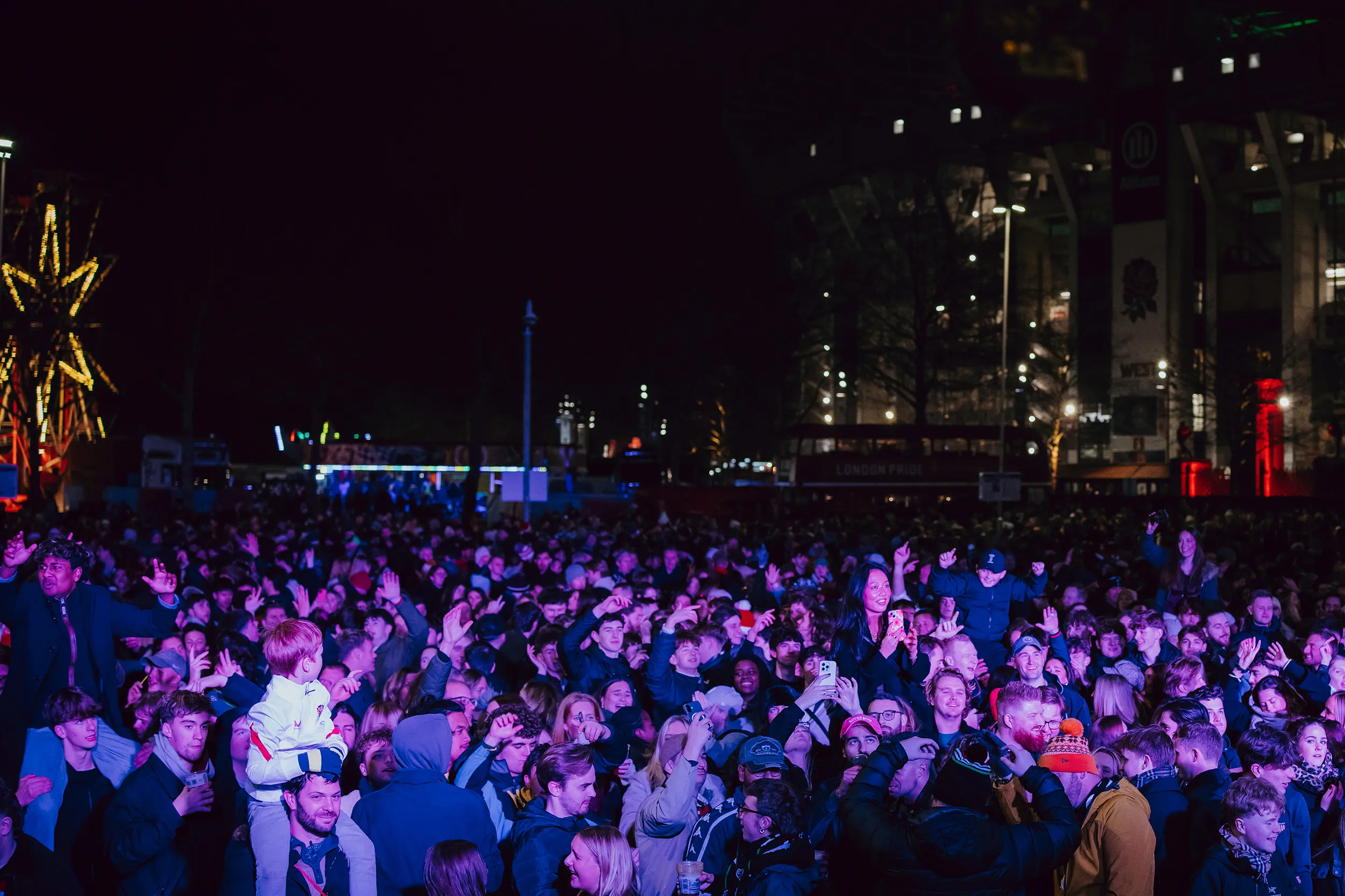 The crowd in the fan zone outside the stadium at night