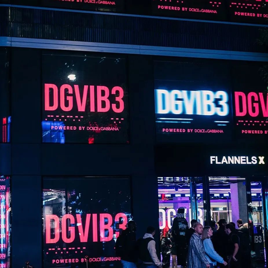 DGVIB3 screens outside the Flannels store at night, crowds queuing below