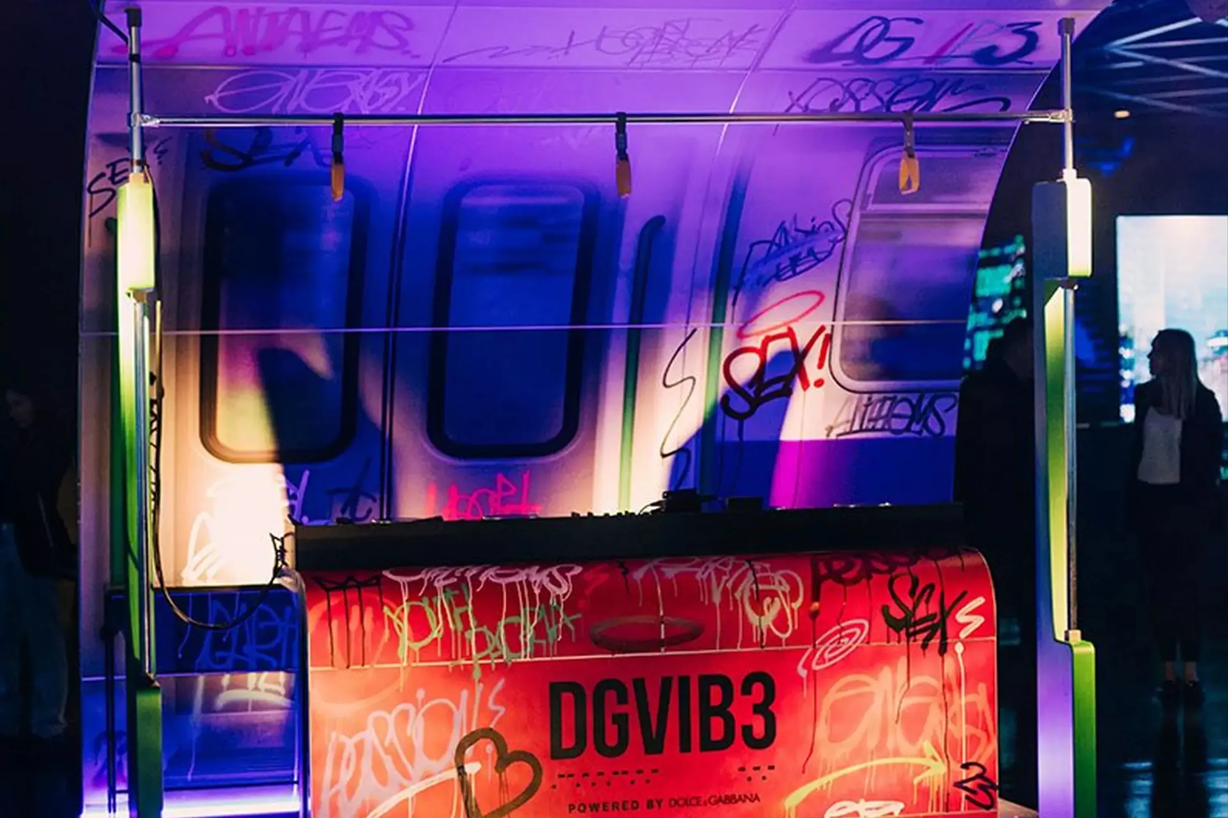 A graffiti-covered tube carriage set lit violet, the DGVIB3 name on the red booth in front