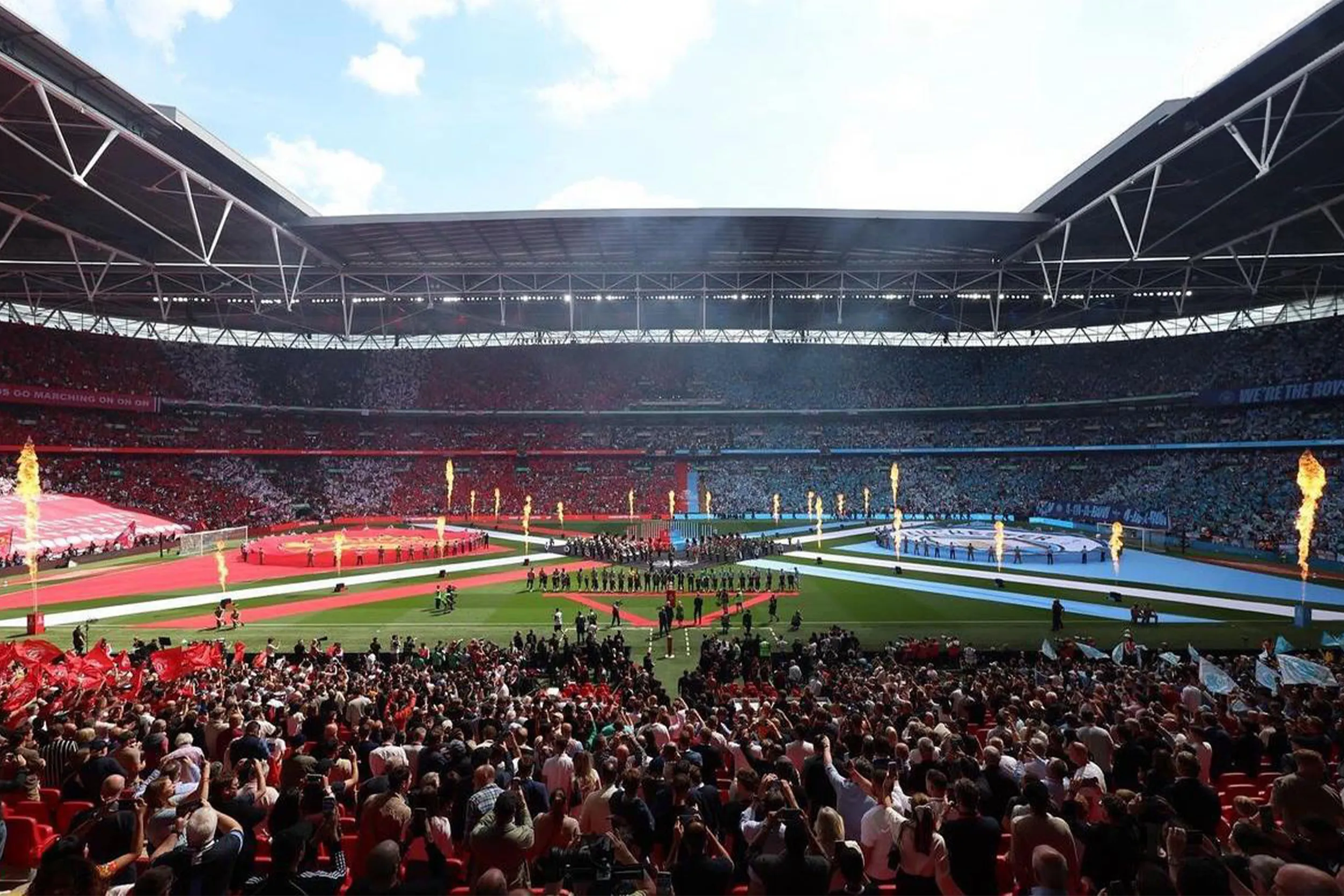 A full Wembley from the stands, flame jets firing along the edge of the pitch display