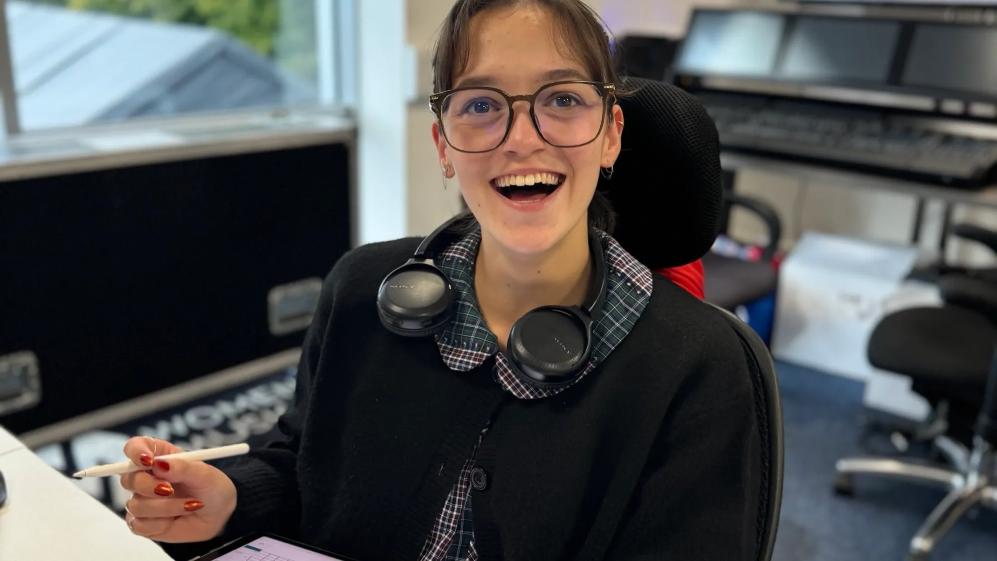 Erin at her desk with a Sony headset around her neck