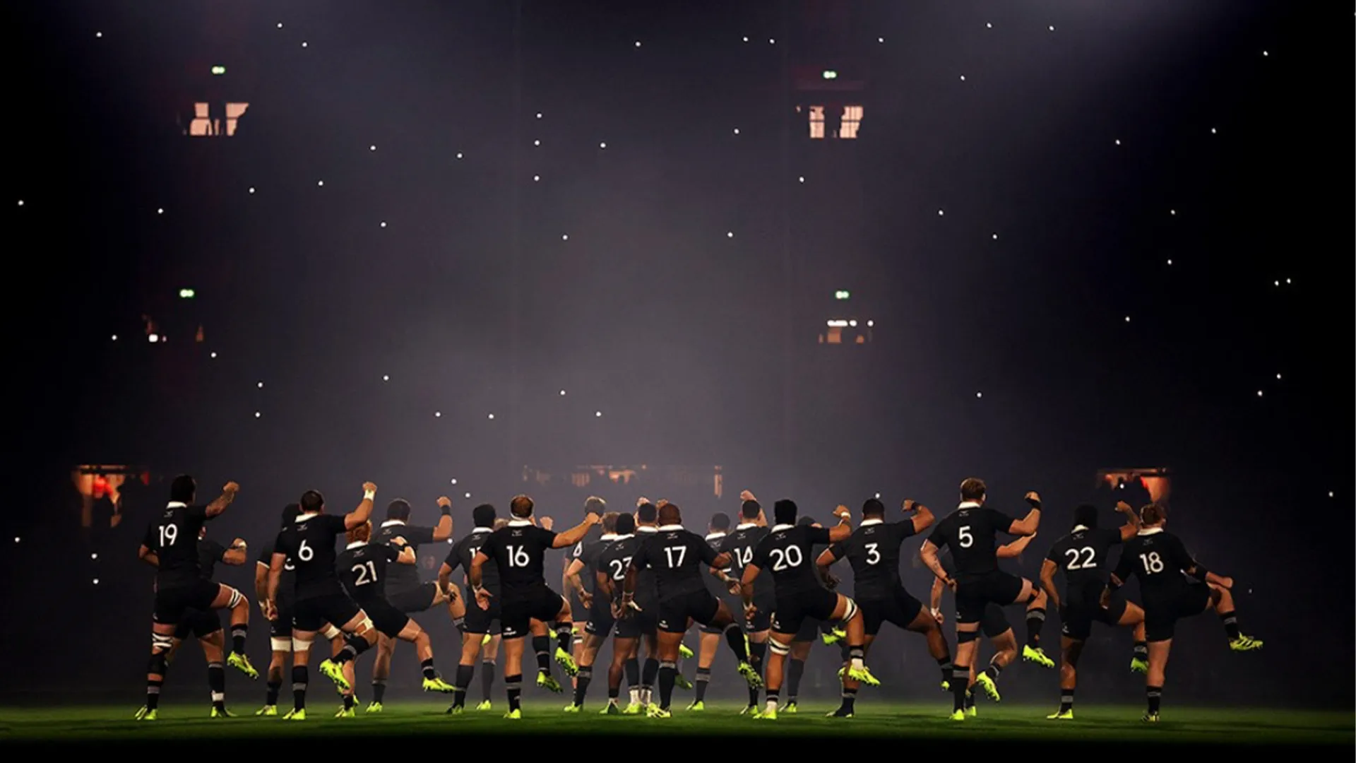 The All Blacks perform the haka, viewed from behind in dramatic lighting