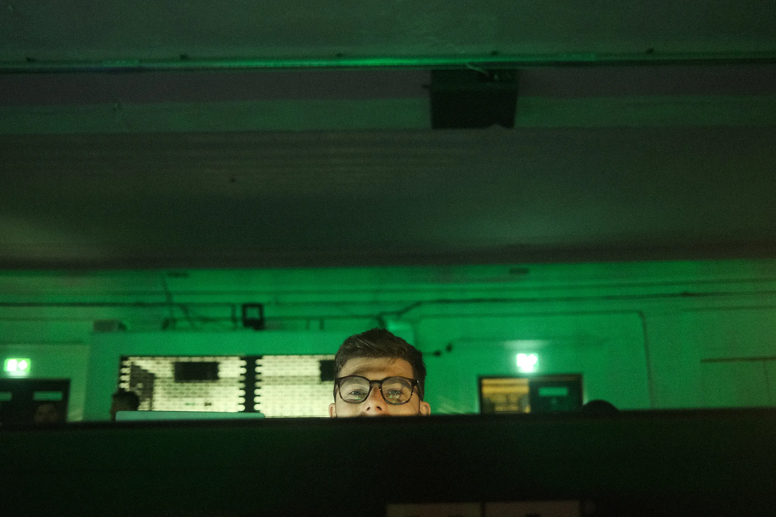 A programmer at the lighting desk under a green wash