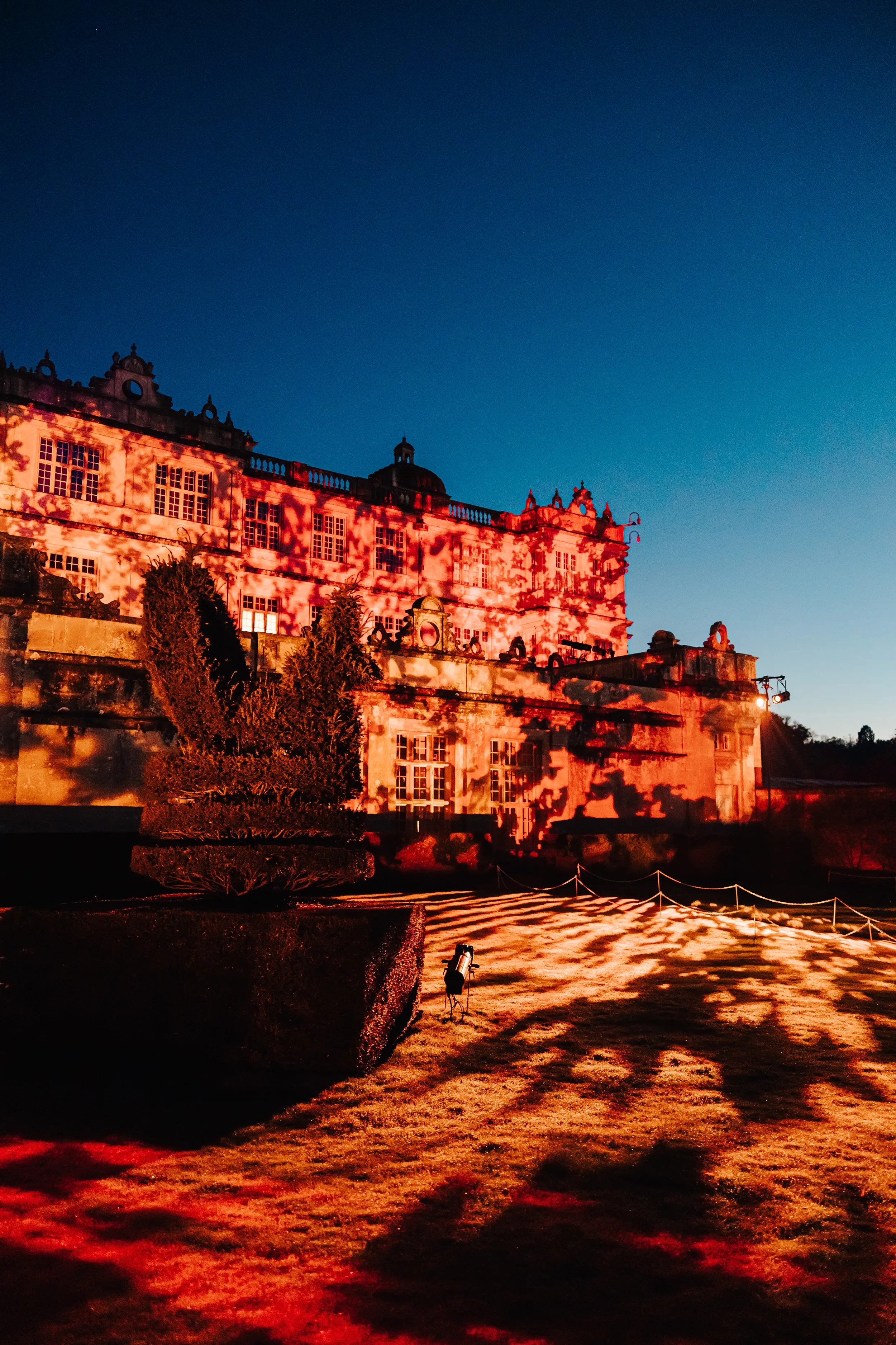 Longleat House lit in projected orange gobo patterns at dusk