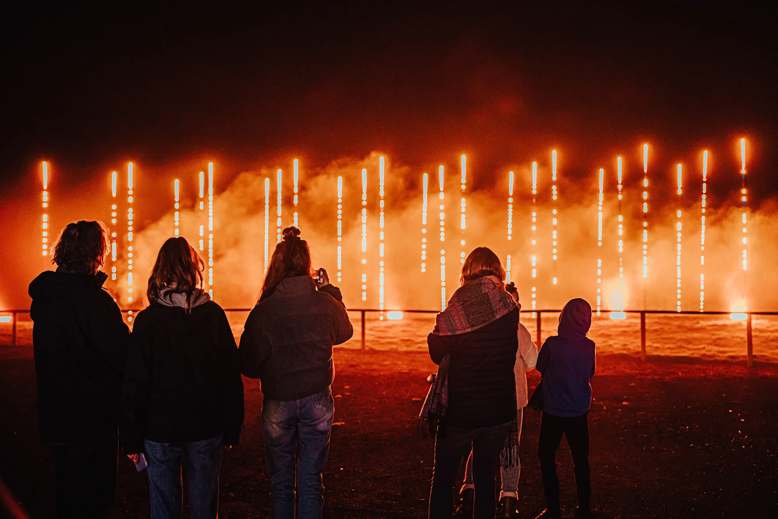 A family watching columns of orange light rise out of haze
