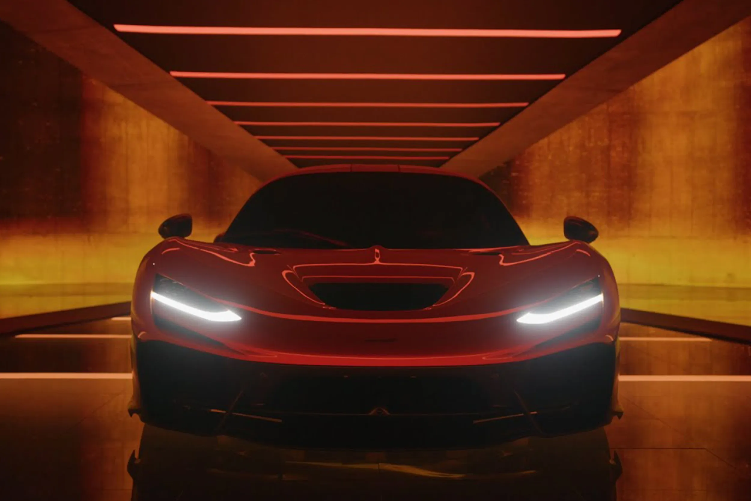 The McLaren W1 head-on in a low tunnel of amber light, its headlights glowing