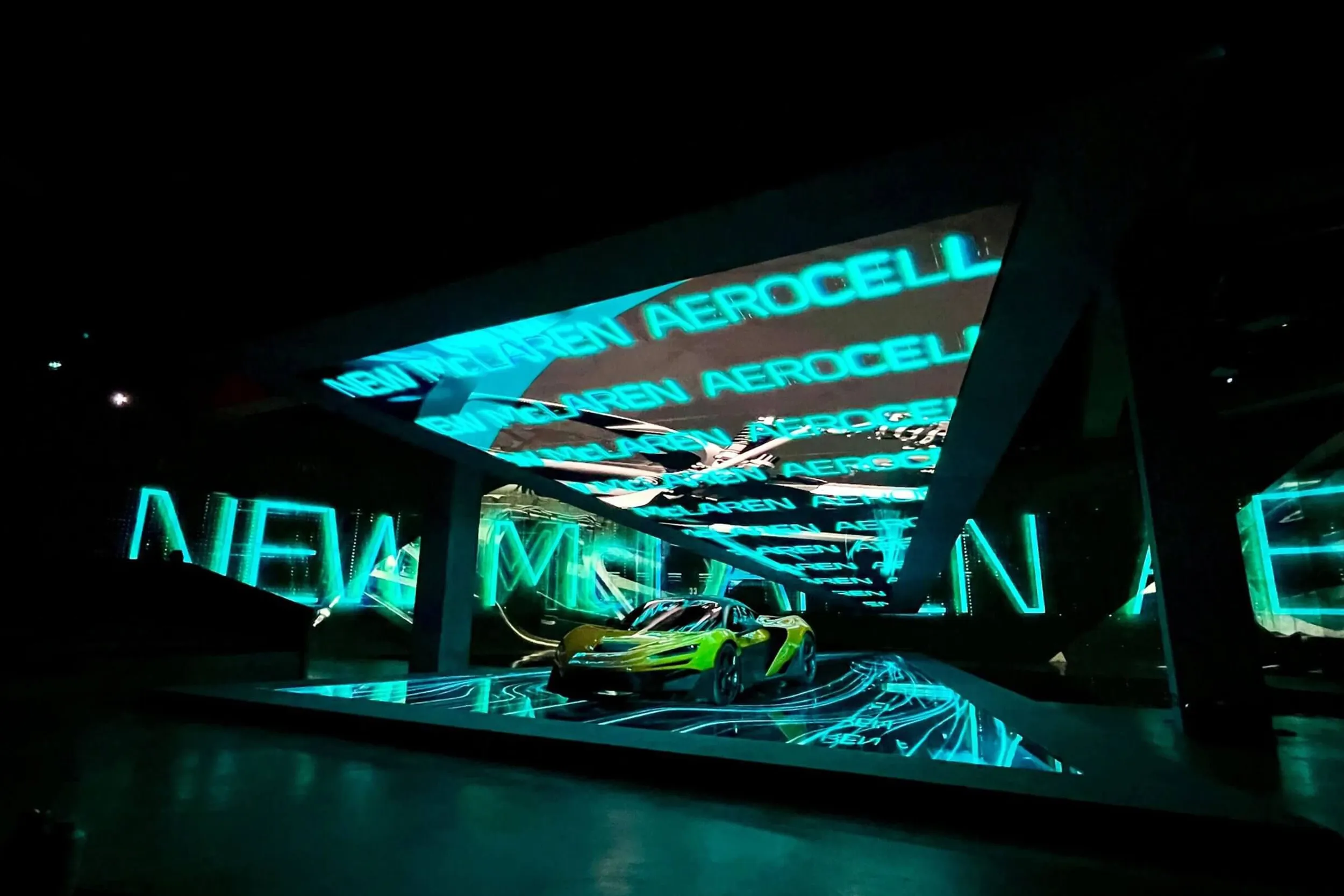 The car under a cyan canopy of visuals spelling out new McLaren Aerocell
