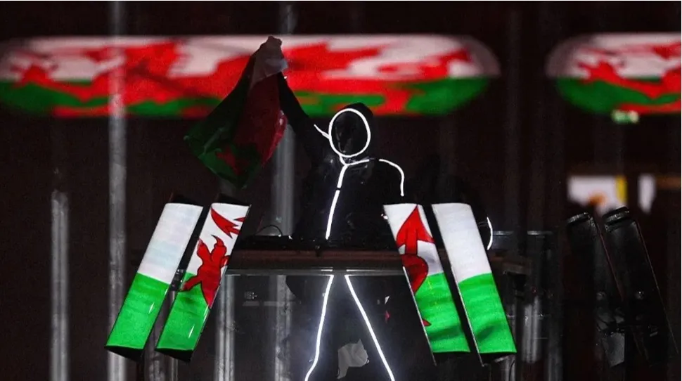 An illuminated stick-figure performer waves a Welsh flag during a Six Nations halftime show