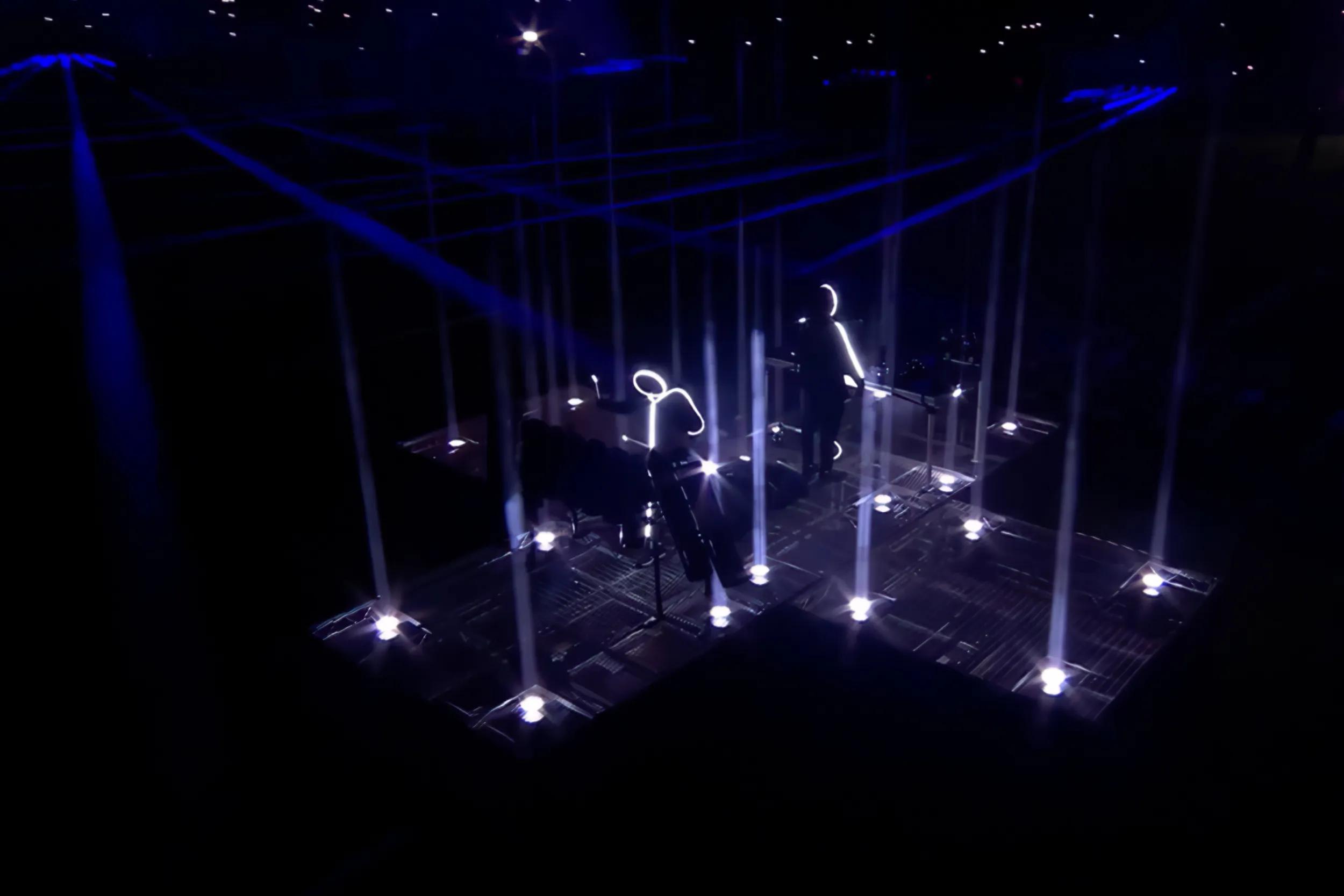 Looking down on the stickmen's stage on the pitch, a grid of white beams rising from the deck in the dark