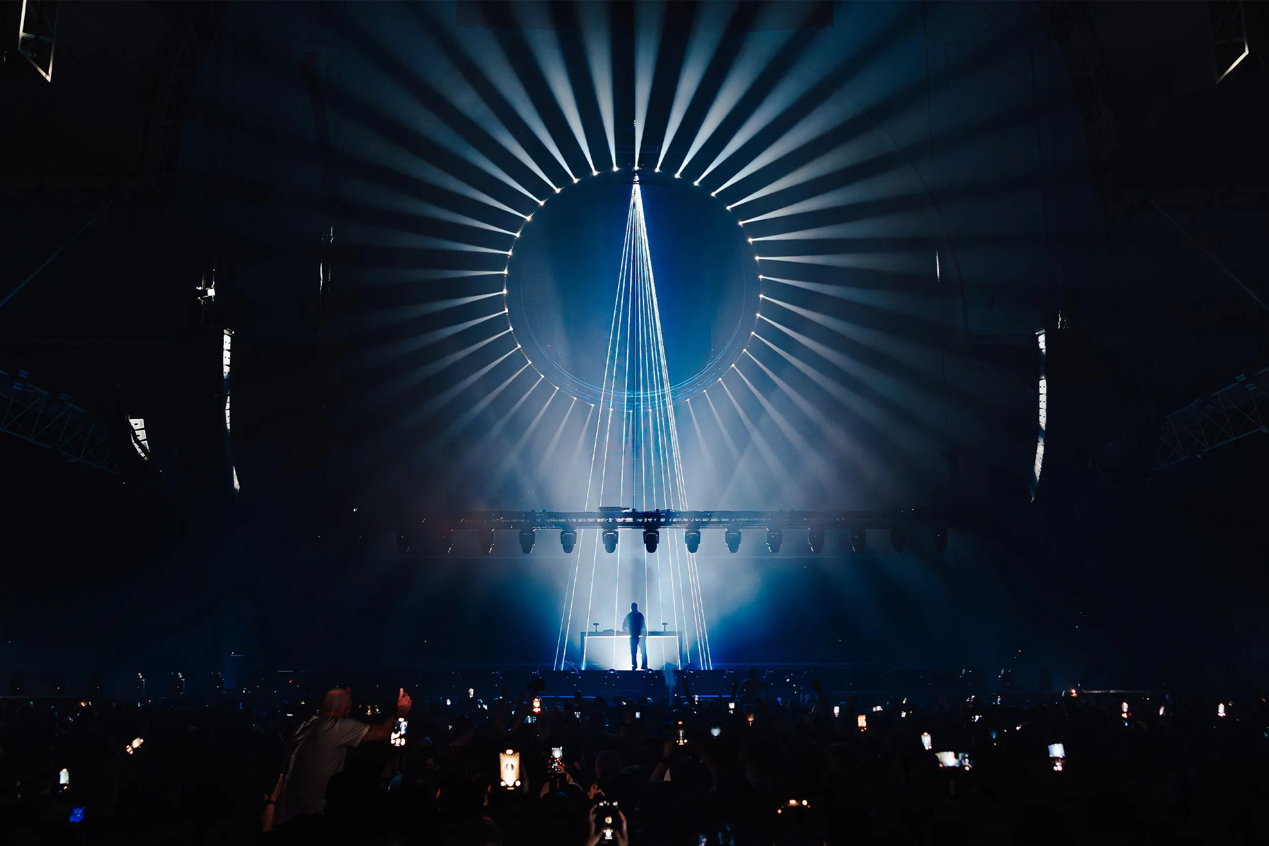 A ring of white beams around a dark circle, a narrow fan of light falling to the booth below