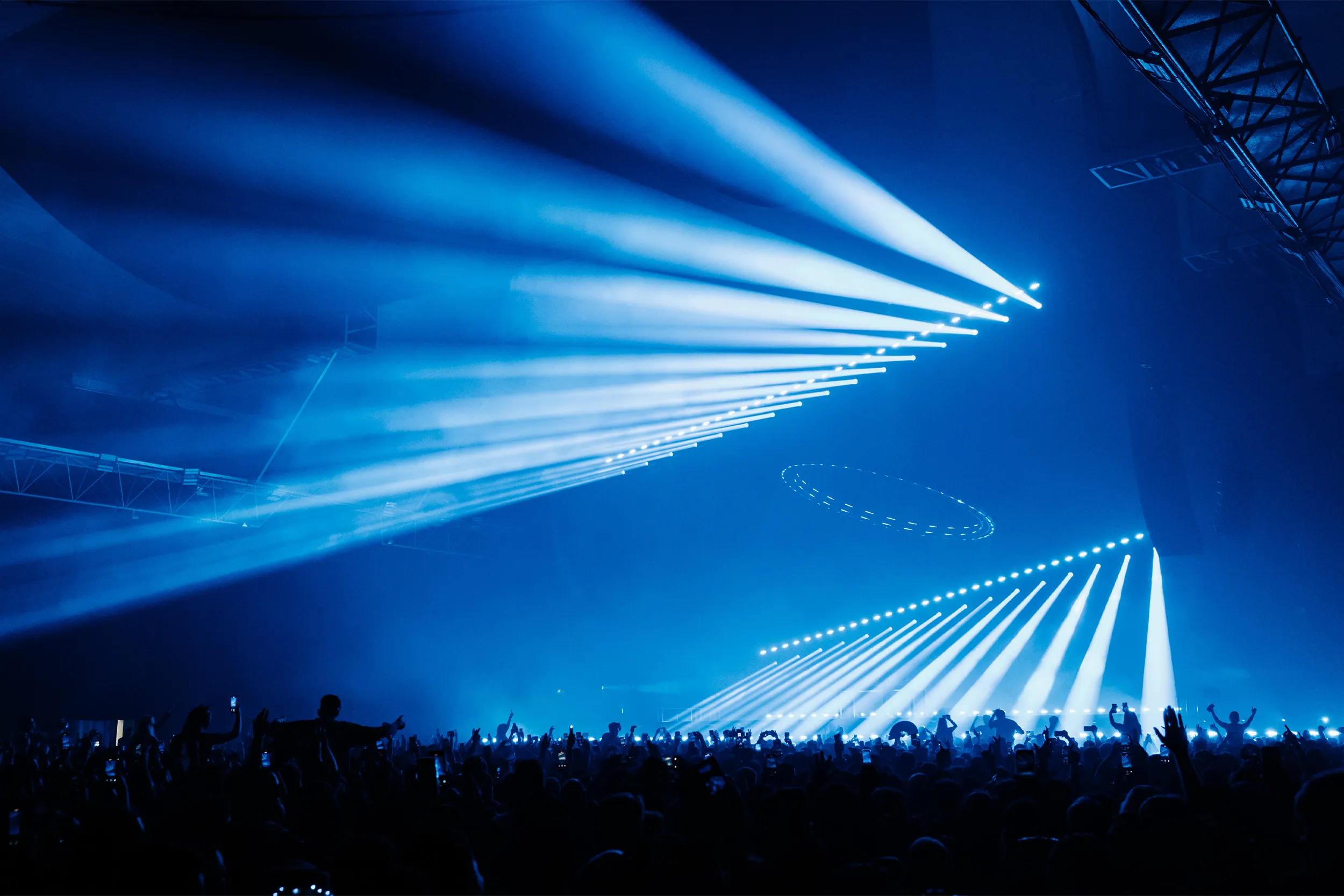 Blue beams sweeping sideways across the room from the rig, the crowd below in darkness