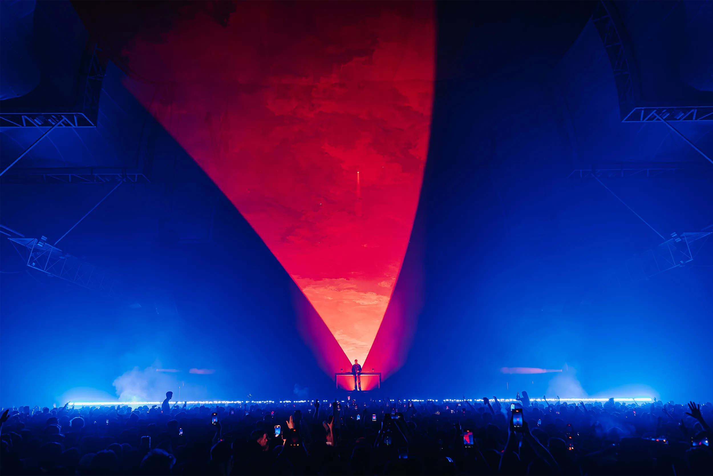 A red cone of light sweeping down to Sub Focus at the decks, the rest of the room in blue